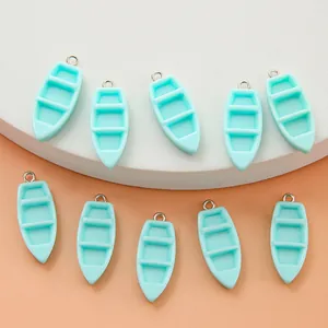 Detail van tien lichtblauwe hars boot hangers met zilveren ringen op stenen plateau