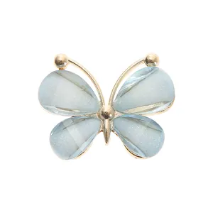 Detail of light blue butterfly shoe charm with gold metal frame and glittery wings
