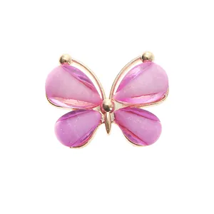 Detailed macro view of a pink butterfly shoe charm with gold glitter and metal frame
