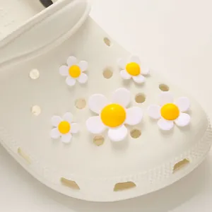 Close-up of five white daisy resin shoe charms attached to a white clog footwear