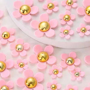 Detail shot of pink resin five-petal flowers with golden metal centers in various sizes