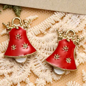 Makroaufnahme roter Emaille-Weihnachtsglocken mit goldenem Elchgeweih auf weißer Spitze