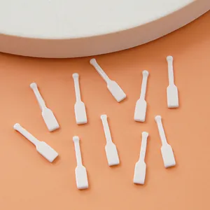 Set van 10 witte plastic cosmetische spatels voor gezichtscrème op een perzikkleurige basis