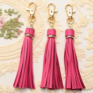 Detailed view of hot pink leather tassel charms with gold lobster clasps for handbags