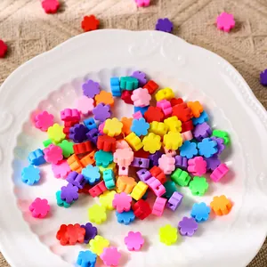 Gros plan de perles de fleurs en résine colorées pour bijoux DIY sur une assiette blanche