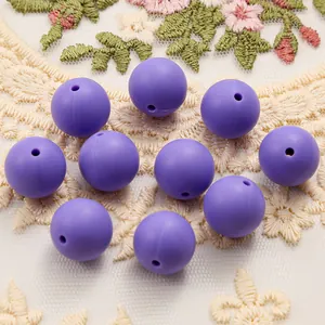 Macro shot of 15mm purple matte silicone beads on lace background for DIY craft projects