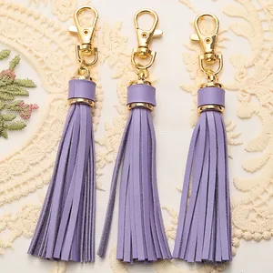 Three light purple PU leather tassels with gold lobster clasps on white lace fabric