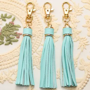Three mint green leather tassel charms with gold lobster clasps on a lace background