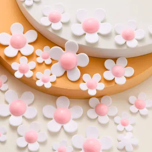 Detailed view of white resin flower charms with pink centers in two sizes for DIY