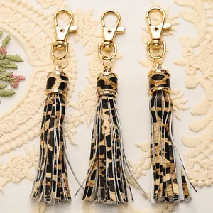Detailed view of leopard print PU leather tassels with gold lobster clasps on lace fabric