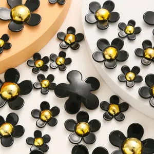 Detail shot of assorted sizes black resin five-petal flower charms with golden center