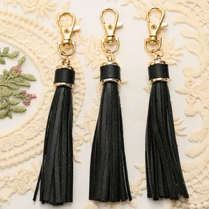 Close-up of black PU leather tassel keychains with golden metal clasps on lace fabric