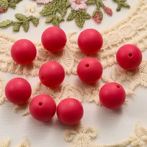 Detail of ten 15mm red matte silicone beads for DIY jewelry making on lace fabric