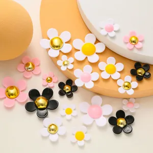 Macro detail of mixed resin daisy charms in pink, black, and white for DIY shoe decoration