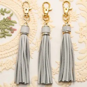Three light gray PU leather tassels with polished golden lobster clasps on lace