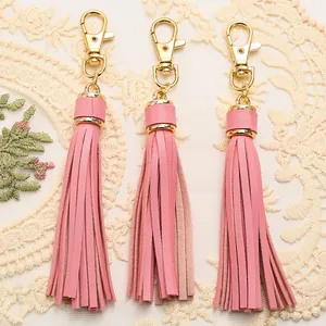 Close-up of pink PU leather tassels with gold lobster clasps on lace background