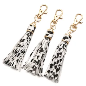 Three-piece cow print PU leather tassel keychains with golden lobster clasps on white base