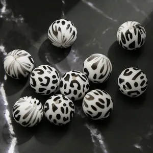 Detailed macro view of 15mm white leopard print silicone beads on dark marble surface
