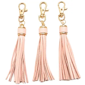 Close-up of three pink faux leather tassels with gold metal lobster clasps for bag charms