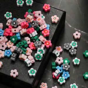 Vue macro de perles fleurs colorées en pâte polymère avec trous latéraux pour création DIY