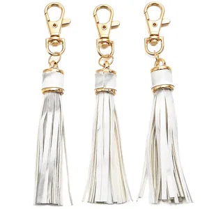 Close-up of white PU leather tassels with gold metal lobster clasps for DIY crafts
