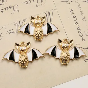Detailed view of three bat charms with gold metal edges and black and white enamel finish