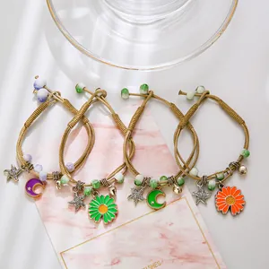 Handmade woven bracelets with star, moon, and daisy charms on a gift card background