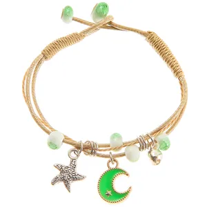 Detail of hand-woven bracelet with starfish, green crescent moon and small bell charms