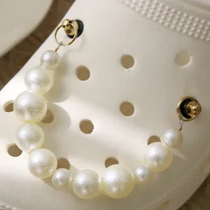 Détail de chaîne en perles de résine blanche pour sabots avec anneaux dorés et boucles