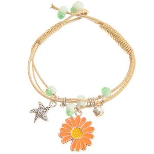 Detail of woven khaki rope bracelet featuring daisy, starfish charms and green beads