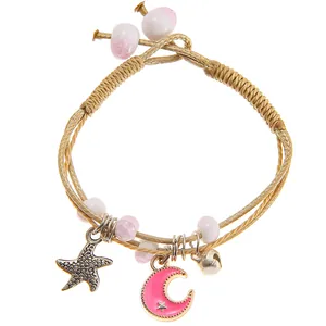 Close-up of woven rope bracelet with pink moon star pendant and starfish charm