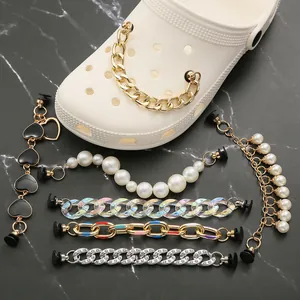 Détail de chaînes en perles et métal pour sabots sur un fond en marbre chic