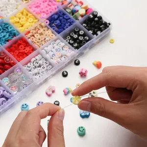 Gros plan de mains enfilant une perle du kit créatif de 24 compartiments pour bijoux