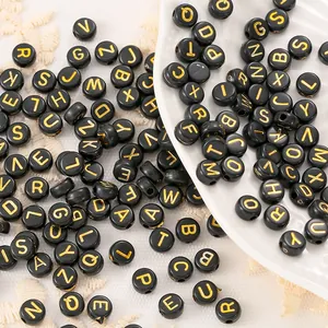 Close-up of black acrylic letter beads with gold initials for DIY jewelry making