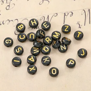 Macro detail of black resin alphabet beads with gold lettering for DIY jewelry making