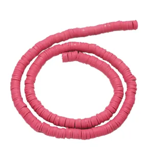 Macro shot of 6mm hot pink polymer clay heishi beads arranged in a spiral on white background