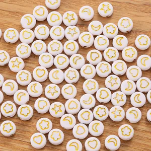 Macro shot of white resin beads with gold star, heart, moon and flower patterns