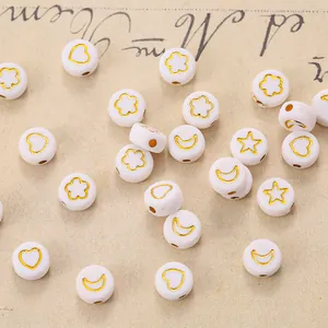 Macro detail of white resin beads with gold heart and star patterns for DIY jewelry making