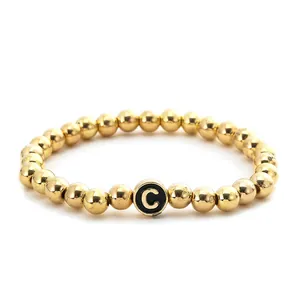 Detailed close-up of golden alloy beaded stretch bracelet with letter C pendant