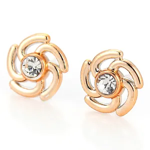 Détail d'une boucle d'oreille en or rose avec un cristal central et motif tourbillon