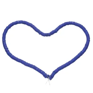 Macro shot of 6mm navy blue heishi beads arranged in a heart shape on a white background