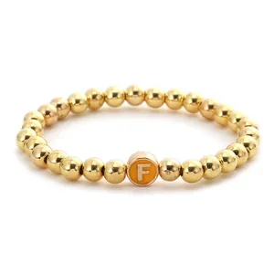 Fashionable golden beaded elastic bracelet with a round orange letter F pendant