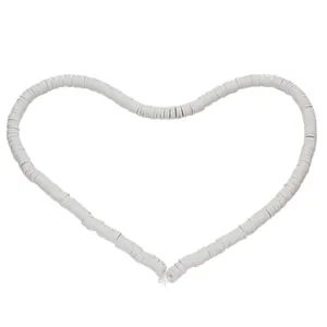 Macro view of white heishi clay beads arranged in a heart shape for jewelry making