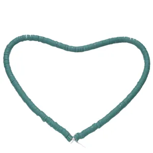 Macro detail of dark green polymer clay heishi beads arranged in a creative heart shape