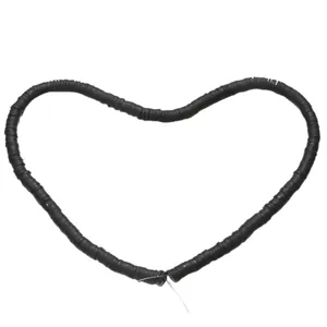 Macro shot of 6mm black polymer clay heishi beads arranged in heart shape for DIY jewelry