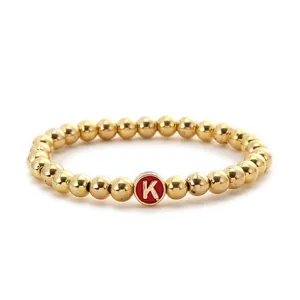 Macro detail of alloy beaded bracelet with golden beads and a red letter K pendant