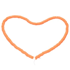 Detail of orange heishi clay beads arranged in a heart shape for DIY jewelry making