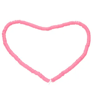 Pink polymer clay heishi beads arranged in a heart shape for DIY jewelry making