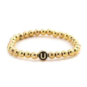 Macro shot of gold-plated metal beads bracelet with a black and gold letter U bead detail