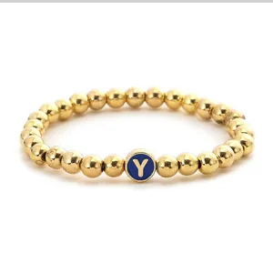Close-up of golden beaded stretch bracelet featuring a blue round initial Y charm